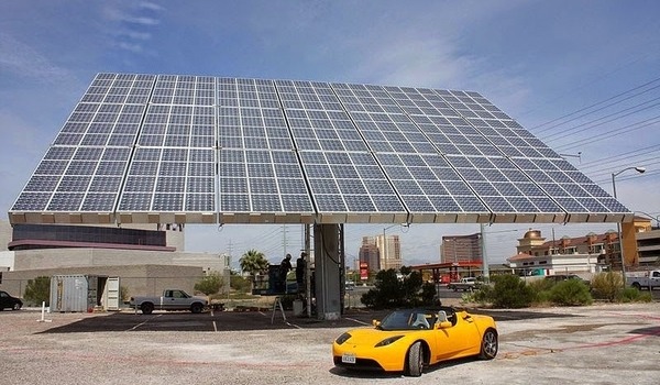 Tesla EV in front of solar panels