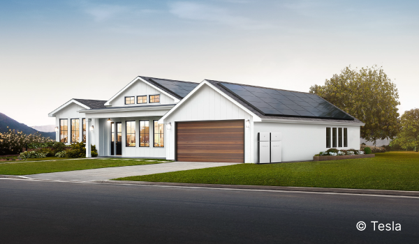Image shows a white house with an attached garage. The home has rooftop solar panels.